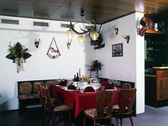 Speisesaal Ein stilvoll gedeckter Tisch in einem rustikal dekorierten Speisesaal mit Geweihen an der Wand.