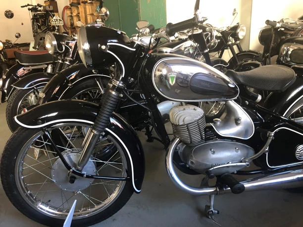 Alte Motorräder aus verschiedenen Jahrzehnten stehen eng beieinander in einem Museumsausstellungsraum.