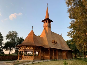 Rumänisch-Orthodoxe-Kirche-Sögel-Christian Lögering.jpg Holzkirche mit spitzem Turm und kunstvollen Schnitzereien im warmen Abendlicht umgeben von Bäumen.