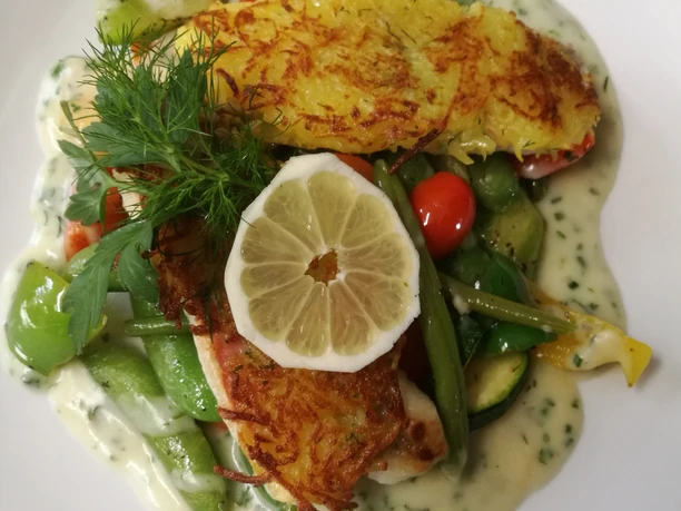 Knurrhahnfilet Auf einem Teller sind goldbraun gebratene Knurrhahnfilets, buntes Gemüse in Sahnesauce und eine Zitronenscheibe angerichtet.