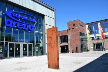 Steinmüllergelände Halle 32 / Schwalbe Arena <p>Die Schwalbe Arena in Gummersbach, eine moderne Halle mit Glasfassade und umliegenden Flaggen.</p>
