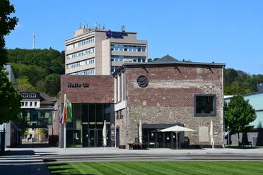 Gummersbacher Kulturzentrum "Halle 32" bei strahlendem Sonnenschein vor grün bewachsenem Hügel.