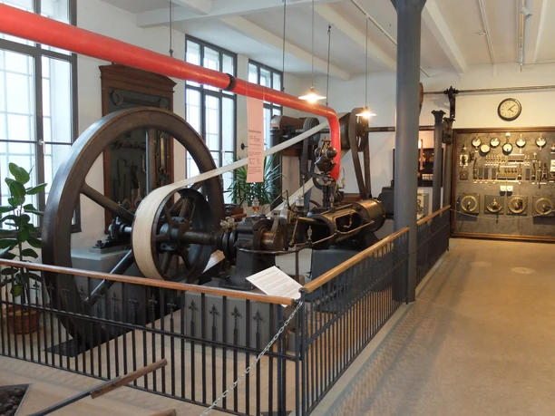 Historic machine in an industrial building, surrounded by information and plants.