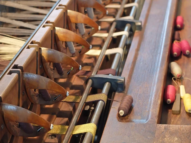 Traditional weaving machine with bobbins in different colors on a wooden surface.