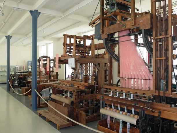 OL_Grossroehrsdorf_MDB_WG_DSCF3188.JPG Historische Webstühle in einem Industriemuseum mit Ausstellungsstücken in einem hellen Raum.