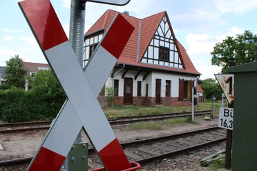 Sudweyher Bahnhof An old half-timbered building with a pitched roof on the railroad track, striking cross in the foreground.