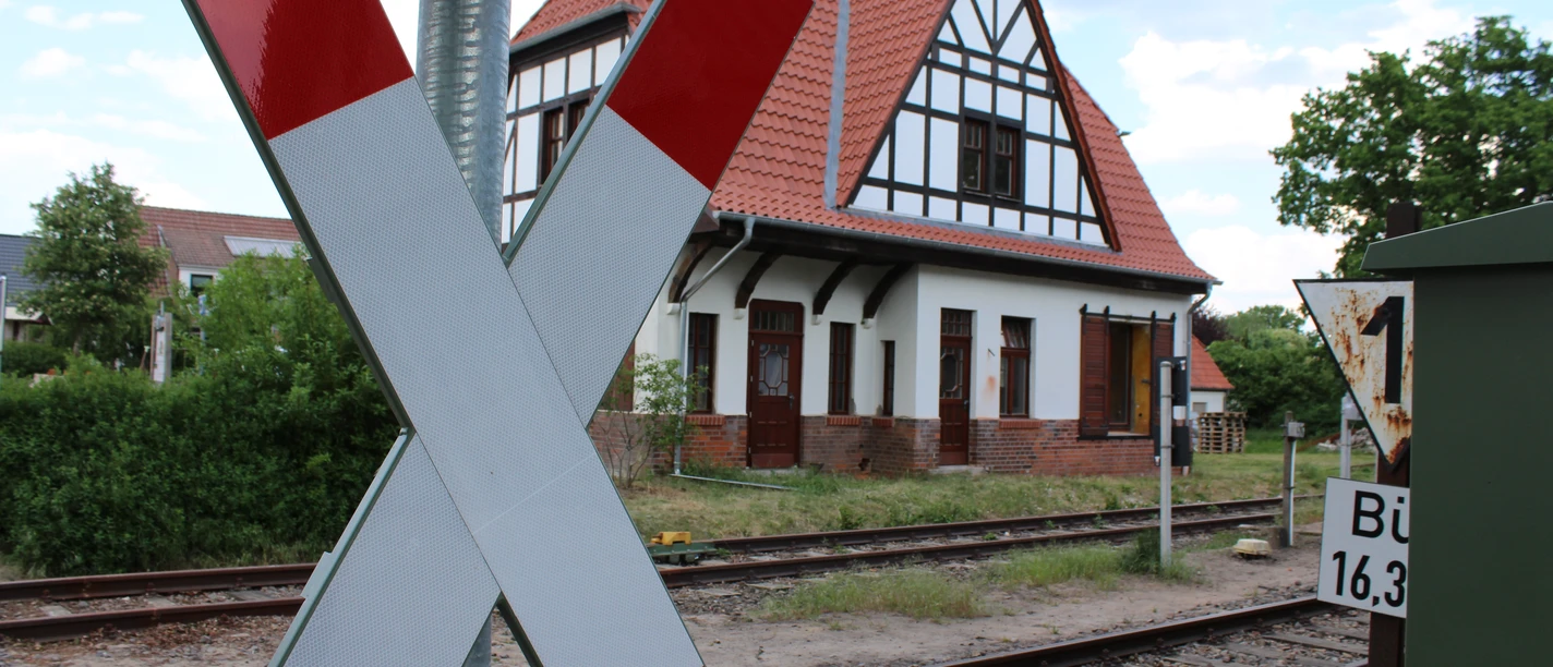 Sudweyher Bahnhof An old half-timbered building with a pitched roof on the railroad track, striking cross in the foreground.