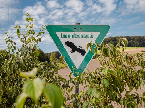 Carolinen Mineralbrunnen - Landschaftsschutzgebiet Ein dreieckiges Schild mit einem schwarzen Eichhörnchen weist auf ein Landschaftsschutzgebiet hin.