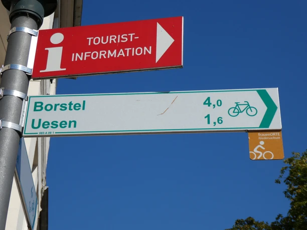 Cato Bontjes van Beek-Radweg Wegweiser zeigt Radrouten-Informationen: Borstel 4 km, Uesen 1,6 km. Blaues Himmelshintergrund.