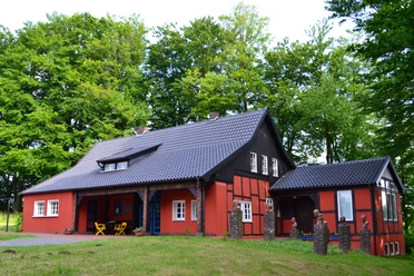 Museum Peter August Böckstiegel, Künstlerhaus Ein charmantes, rotes Fachwerkhaus mit Schieferdach, umgeben von dichtem grünen Wald.