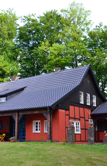 Museum Peter August Böckstiegel, Künstlerhaus Ein charmantes, rotes Fachwerkhaus mit Schieferdach, umgeben von dichtem grünen Wald.