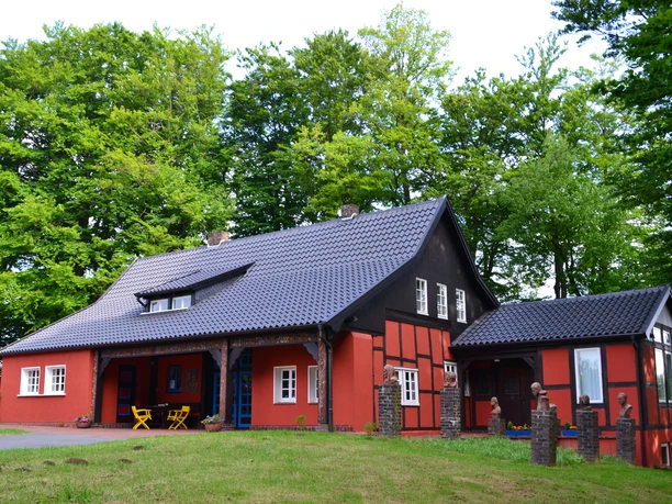 Museum Peter August Böckstiegel, Künstlerhaus Ein charmantes, rotes Fachwerkhaus mit Schieferdach, umgeben von dichtem grünen Wald.