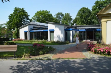 Gesundheitszentrum Ein modernes Gesundheitszentrum mit blauen Vordächern, umgeben von gepflegten Blumenbeeten.