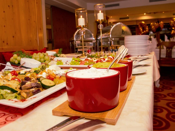 Hotel Goldener Acker Ein Buffet mit roten Schüsseln, gefüllt mit Dips, Gemüseplatten und Kerzen im Hintergrund.