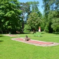Minigolf Minigolfplatz eingebettet in eine grüne Parklandschaft mit roten Bahnen und angrenzenden Bäumen.