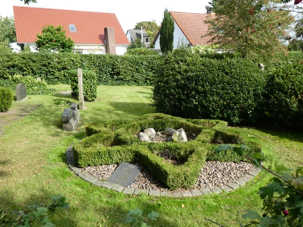Historischer Jüdischer Friedhof in Achim, gepflegte Grünanlage mit älteren Grabsteinen und Hecken.