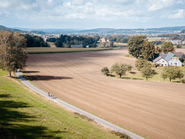 Radfahren in Bad Laer Radfahrer auf schmalem Weg durch weite Felder und sanfte Hügellandschaft.