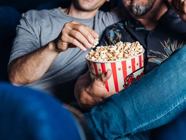 Filme schauen und Popcorn essen im Kino Zwei Personen teilen sich Popcorn im Kino