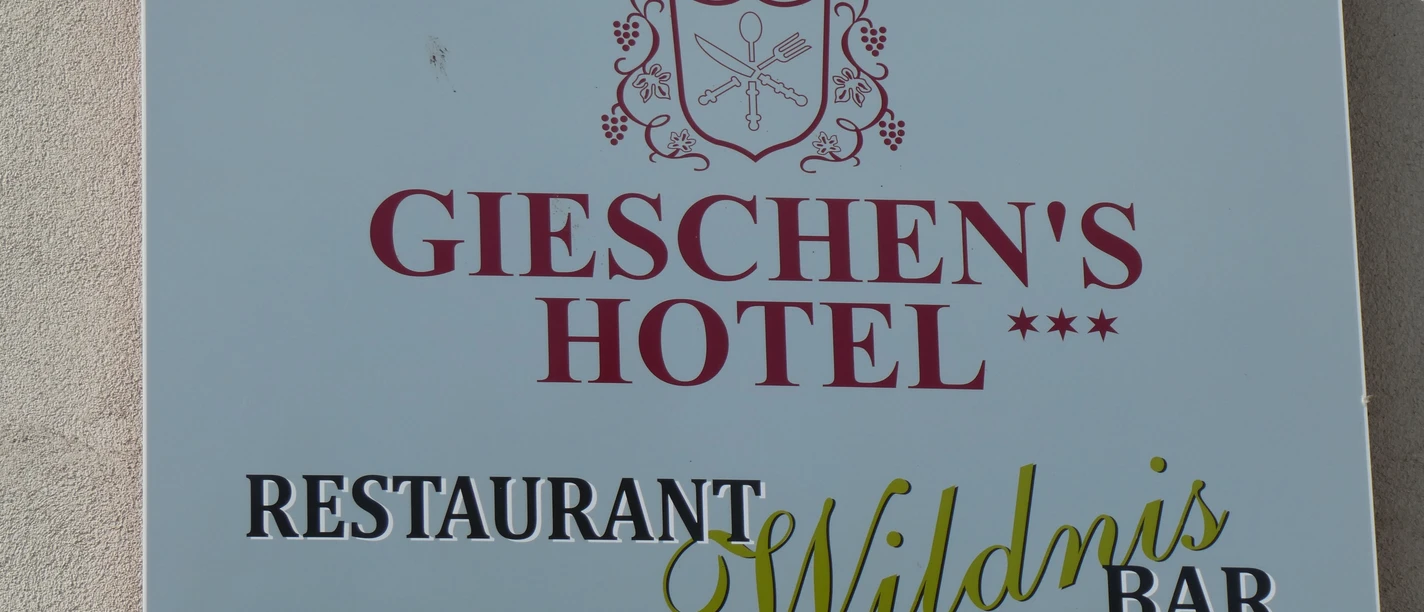 Restaurant Wildnis im Gieschens Hotel Das Bild zeigt ein Schild mit der Aufschrift Gieschen's Hotel und Restaurant Wildnis Bar in elegantem Design.