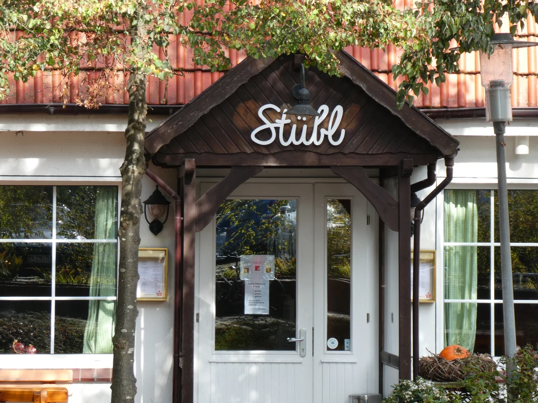 Restaurant Stübl im Landhaus Wesermarsch Eingang des Restaurant Stübl mit Holzveranda, großen Fenstern und Blumen vor der Tür.