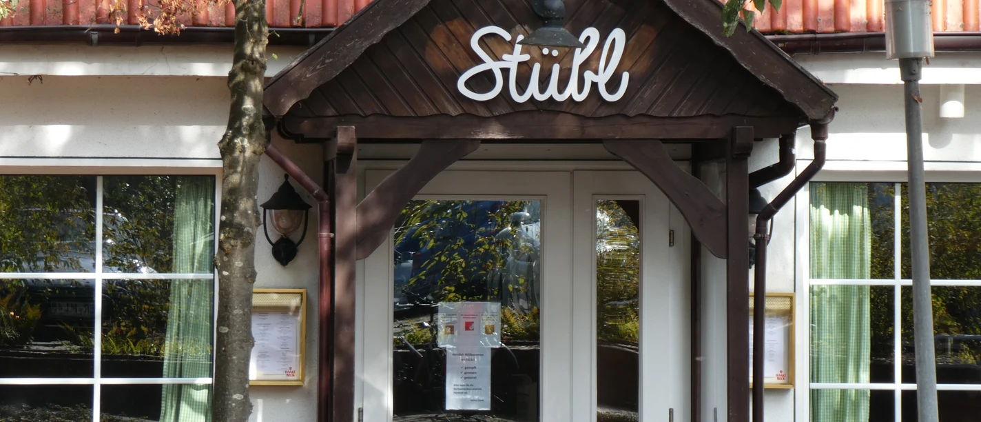 Restaurant Stübl im Landhaus Wesermarsch Eingang des Restaurant Stübl mit Holzveranda, großen Fenstern und Blumen vor der Tür.