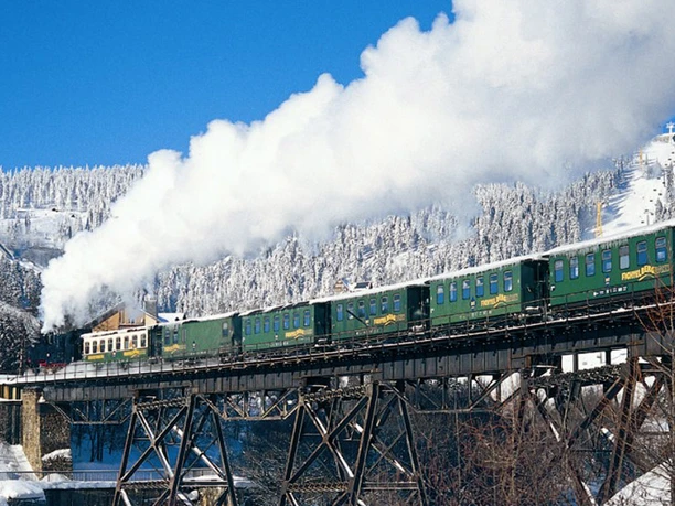 Erzgebirge Fichtelbergbahn Schmalspurbahn mit Dampflok im winterlichen Erzgebirge, frische Schneelandschaft umgeben.