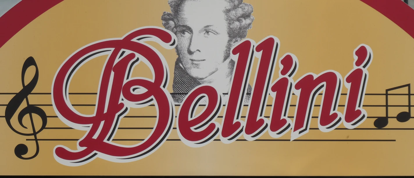 Restaurant Bellini Restaurant Bellini: Logo auf gelbem Schild mit Notenlinien und Porträt von Komponist Vincenzo Bellini.