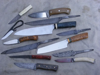 Auswahl handgefertigter Messer Verschiedene handgefertigte Messer in unterschiedlichen Größen und Designs liegen auf einem weißen Hintergrund.