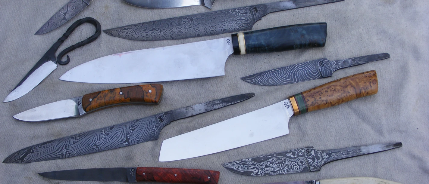 Auswahl handgefertigter Messer Verschiedene handgefertigte Messer in unterschiedlichen Größen und Designs liegen auf einem weißen Hintergrund.