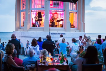 Torsten Dachwitz.jpg Eine sommerliche Musikveranstaltung mit Liveband in einem Pavillon am Meer zieht begeisterte Zuschauer an.