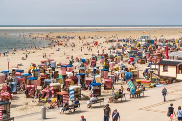 Beach with colorful beach chairs, visitors and sea views. A summer day full of relaxation and activity.