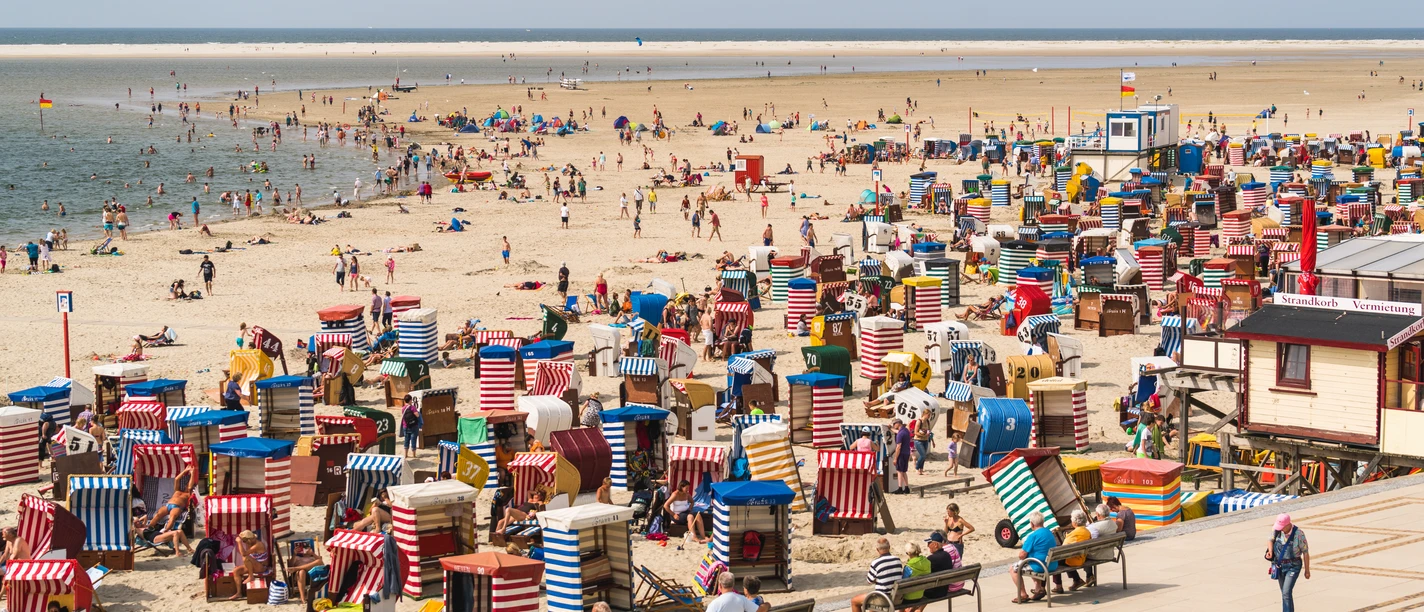 Beach with colorful beach chairs, visitors and sea views. A summer day full of relaxation and activity.