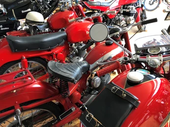 Klassische rote Benelli-Motorräder sind dicht beieinander in einem Ausstellungsraum aufgestellt.