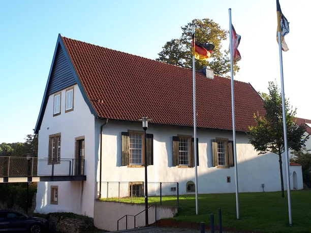 Haus Bissendorf Historisches Gebäude mit Satteldach, umgeben von Flaggen und Grünfläche, Liebenswertes Bissendorf.