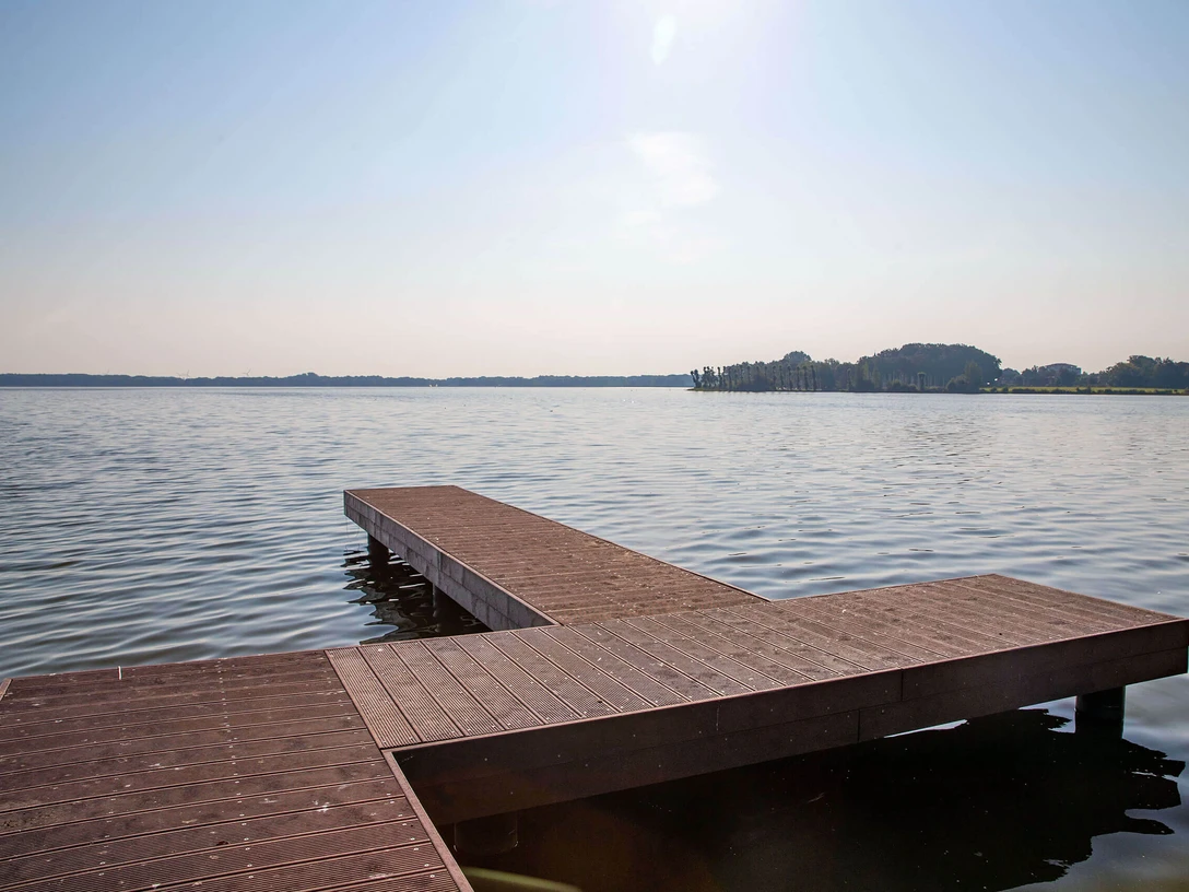 steg-dlrg-zwischenahner-meer.jpg Ein Steg ragt ins Zwischenahner Meer, umgeben von ruhigem Wasser und einem fernen Ufer im Hintergrund.A jetty juts out into the Zwischenahner Meer, surrounded by calm water and a distant shore in the background.En anløbsbro stikker ud i Zwischenahner Meer, omgivet af roligt vand og en fjern kyst i baggrunden.Een steiger steekt uit in het Zwischenahner Meer, omgeven door kalm water en een verre kust op de achtergrond.