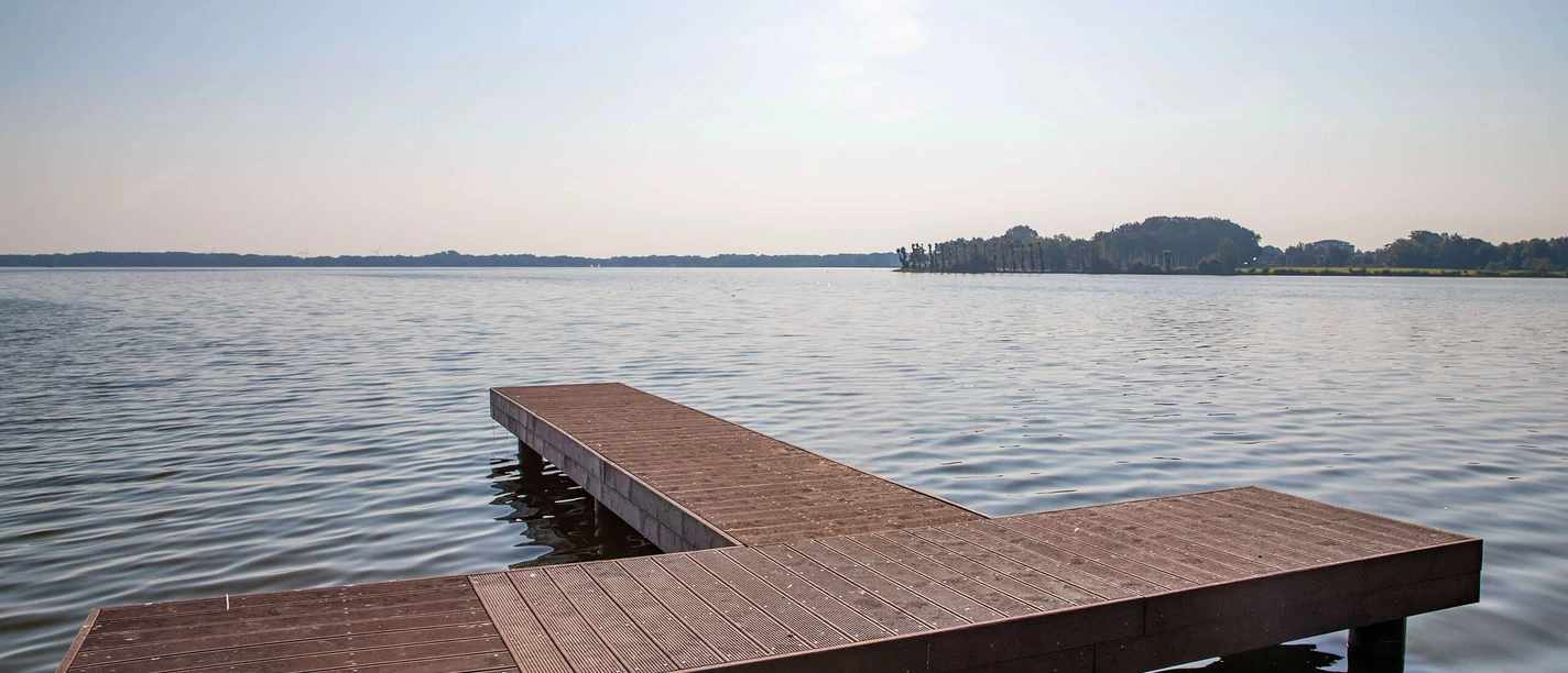 steg-dlrg-zwischenahner-meer.jpg En anløbsbro stikker ud i Zwischenahner Meer, omgivet af roligt vand og en fjern kyst i baggrunden.