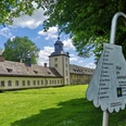 Weltkulturerbe Schloss Corvey mit parkähnlicher Anlage, von Pilgerwegweiser im Vordergrund ergänzt.