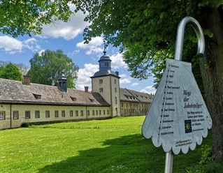Corvey als Pilgerziel Weltkulturerbe Schloss Corvey mit parkähnlicher Anlage, von Pilgerwegweiser im Vordergrund ergänzt.