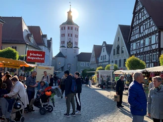 Herbstmarkt in Günzburg. Ein sonniger Herbstmarkt in Günzburg, mit Besuchern und Marktständen vor historischen Gebäuden.