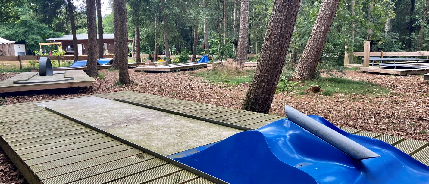 Minigolf im Wald.jpg Minigolfanlage im dichten Wald, gepflegte Bahnen, naturbelassene Umgebung mit hohen Bäumen.