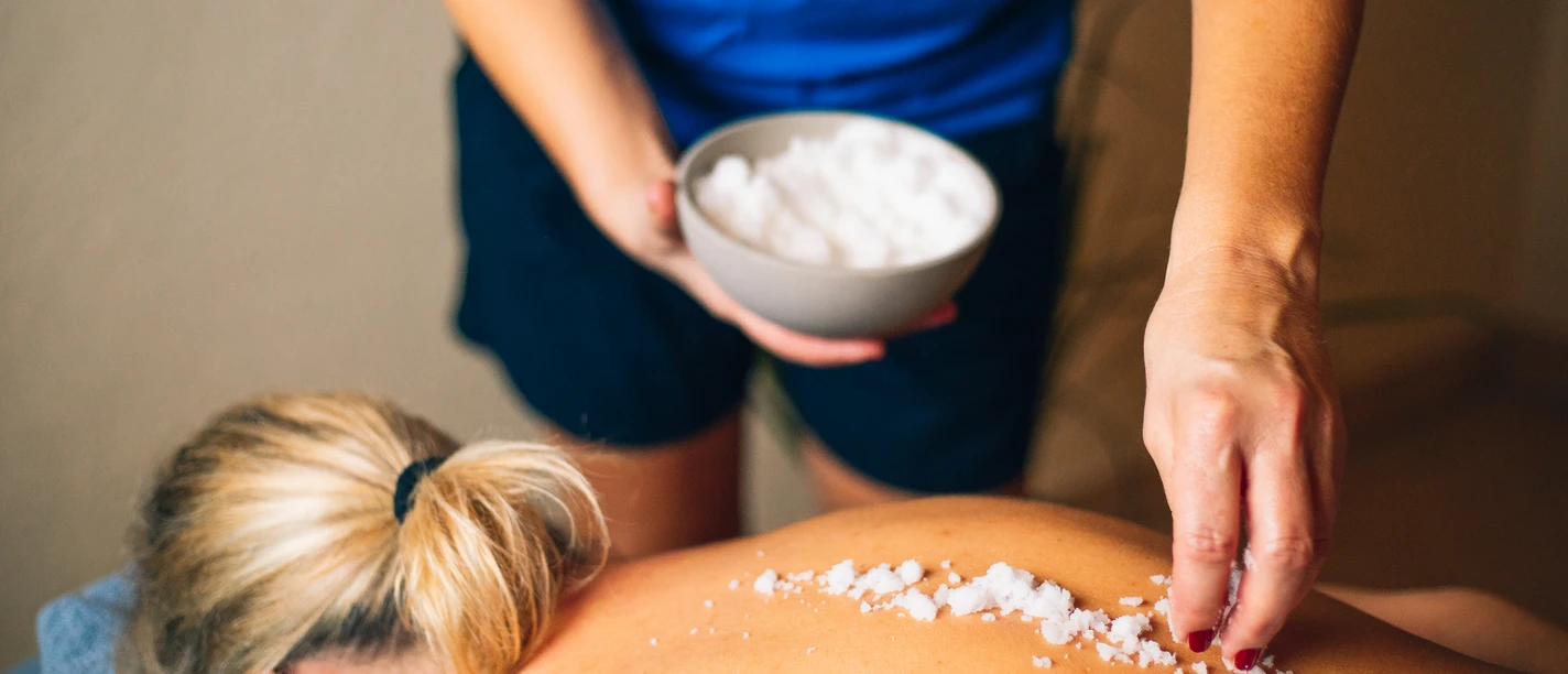 Eine Frau genießt eine Salzbehandlung auf dem Rücken im Wellnessbereich.A woman enjoys a salt treatment on her back in the wellness area.