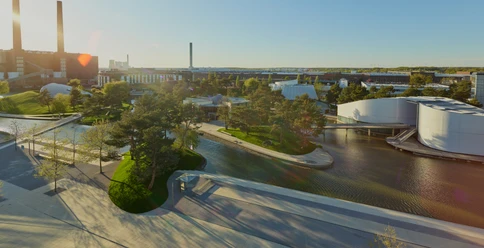 Autostadt Panorama Weitläufige Parklandschaft der Autostadt Wolfsburg mit Wasserflächen, modernen Pavillons und Schornsteinen.