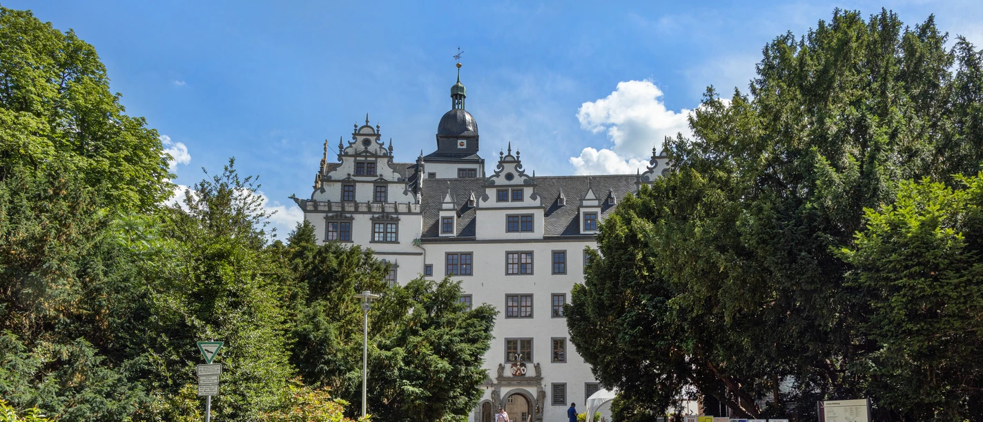 Schloss Wolfsburg Außenansicht Renaissance-Schloss mit weißer Fassade und Türmen, umgeben von Bäumen unter blauem Himmel.