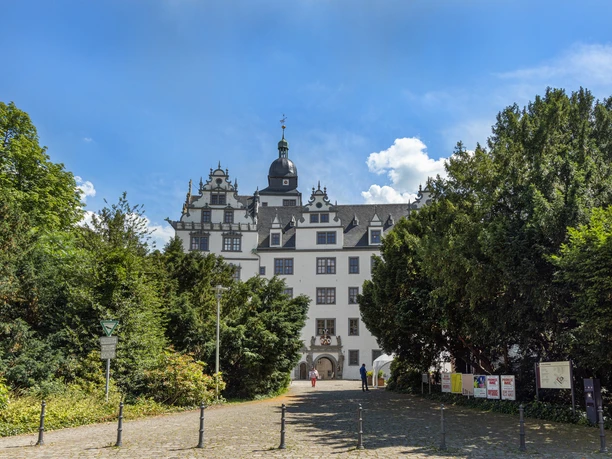 Schloss Wolfsburg Außenansicht Renaissance-Schloss mit weißer Fassade und Türmen, umgeben von Bäumen unter blauem Himmel.