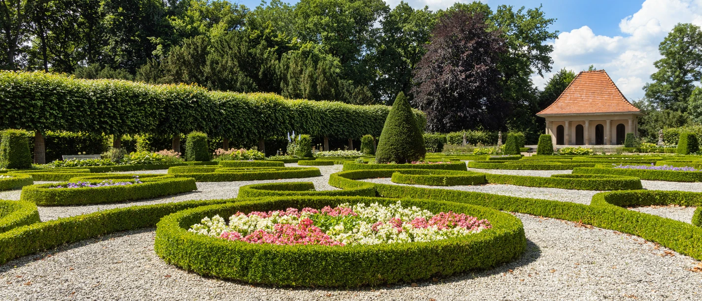 Schloss Wolfsburg Barockgarten Barockgarten mit symmetrisch angelegten Beeten, Buchsbaumhecken und Pavillon im Hintergrund.