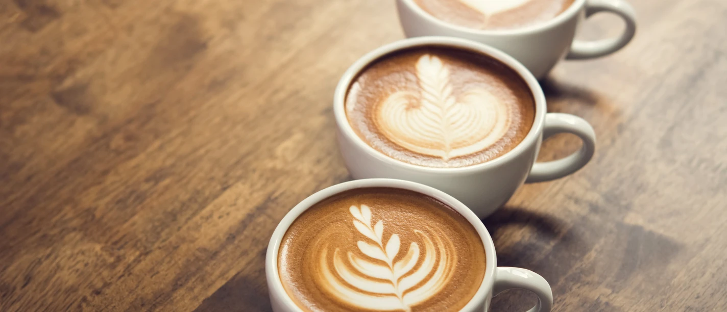 Cappuccino Drei Cappuccino-Tassen mit Muster im Kaffeeschaum