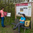 Zwei Frauen erkunden einen Lehrpfad mit Infotafeln über die Eiszeit in einer ländlichen Umgebung.Two women explore an educational trail with information boards about the Ice Age in a rural setting.To kvinder udforsker en undervisningssti med informationstavler om istiden i landlige omgivelser.Twee vrouwen verkennen een educatief pad met informatieborden over de ijstijd in een landelijke omgeving.