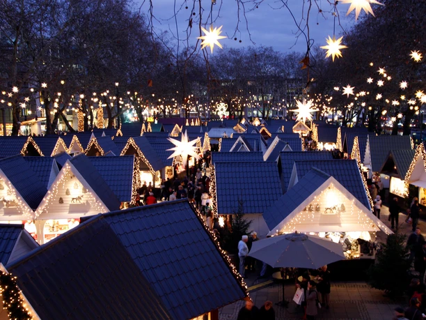 Market of Angels in Cologne Magically illuminated Christmas market with star-shaped lights and huts under the open sky.