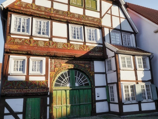 Haus Hemmelmann in Wiedenbrück Fachwerkhaus mit verzierten Holzbalken und grüner Holztorfront, Fenster mit Sprossen.