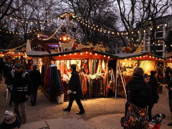 Stadtgarten Christmas market Ein Weihnachtsmarkt mit Ständen, Lichtern und Besuchern im Abendlicht.A Christmas market with stalls, lights and visitors in the evening light.